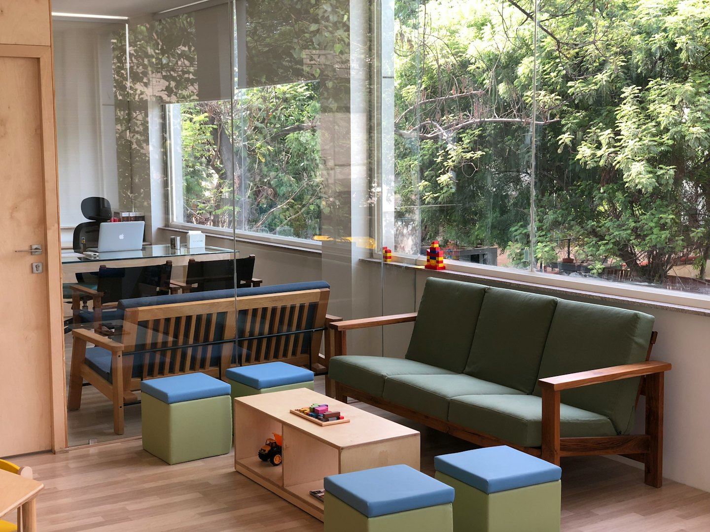 Moderner Bürolounge-Bereich mit hellen Holzmöbeln und grünen Kissen.